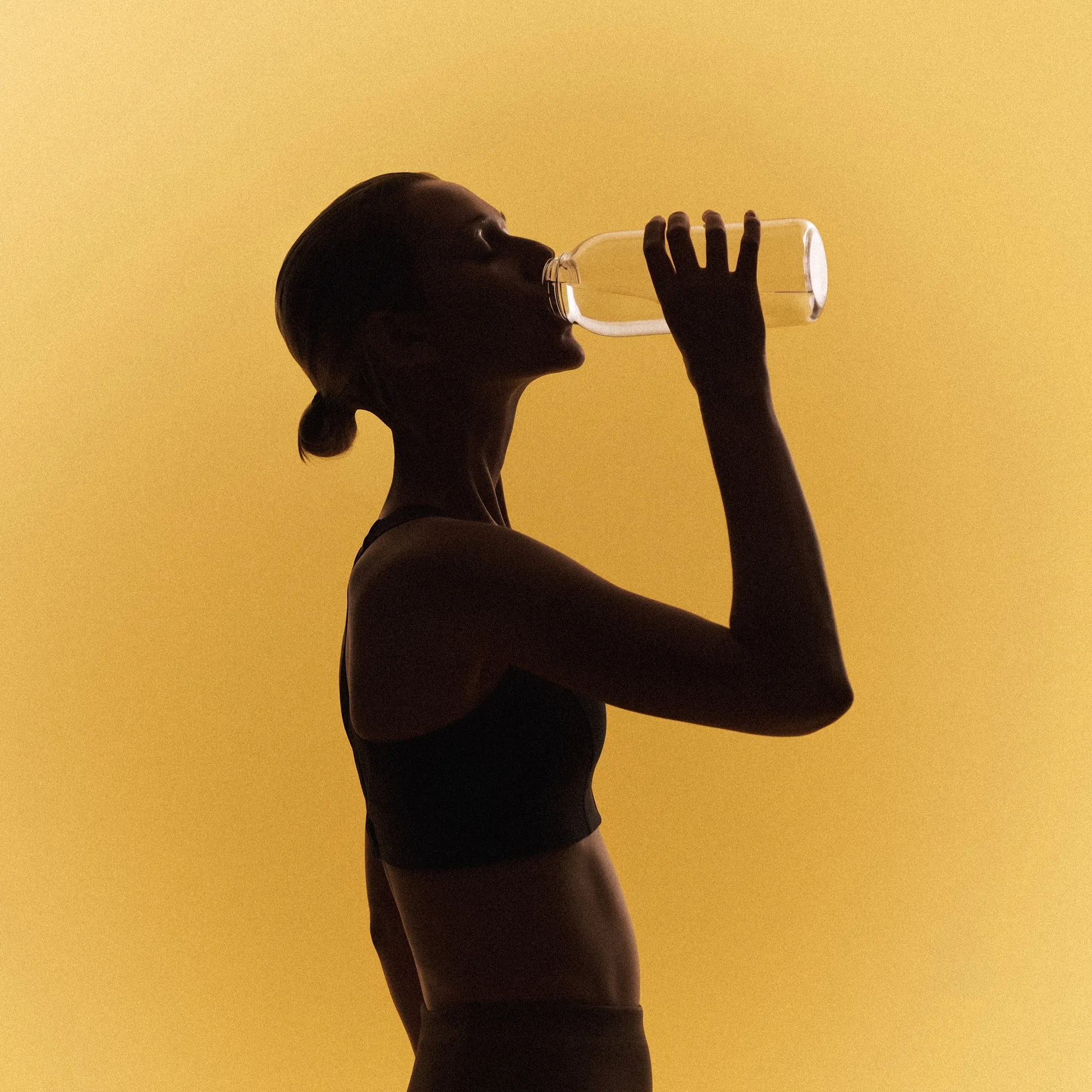 A woman drinking from a water bottle, in silhouette against a warm amber background